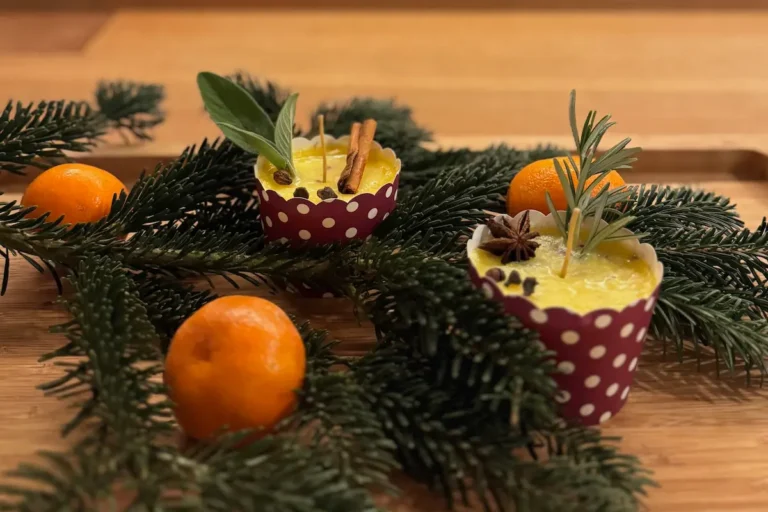 Butterkerze selber machen: Anleitung für eine duftende Kerze aus Kräuterbutter Zwei Butterkerzen und Tannenzweigen, sowie Mandarinen auf dem Tisch