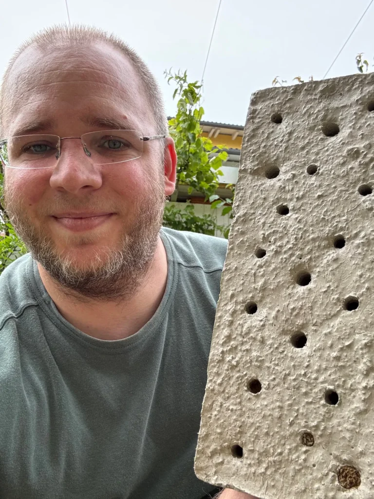 Selfie von einem Mann, mit einem Niststein aus Beton in der Hand.