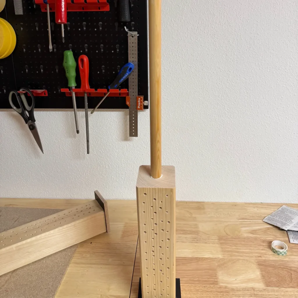 Eine Rundholz wird als Stütze an eine Nisthilfe geklebt.