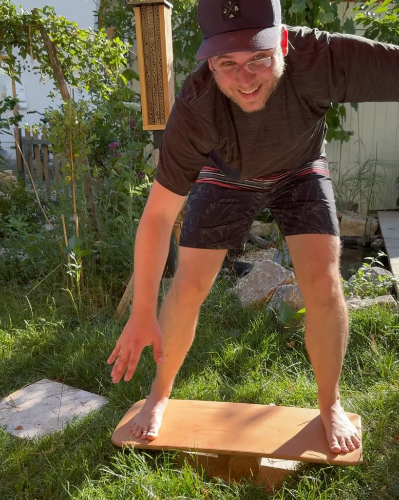 Ein Mann testet ein Balance Board in seinem Garten.