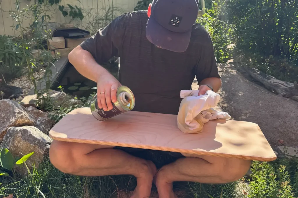 Ein Mann ölt ein Balance Board mit Leinöl ein.