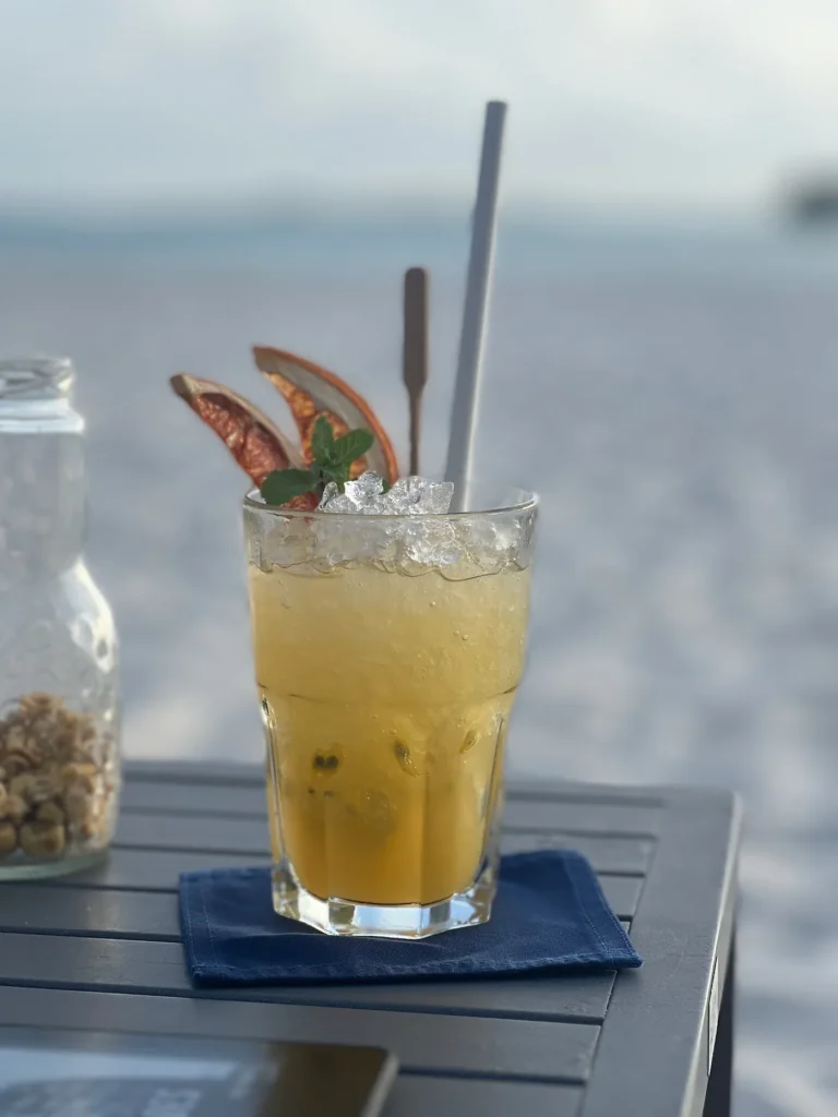 Fruchtiger Cocktail auf einem Tisch. Im Hintergrund die Kulisse der Malediven.