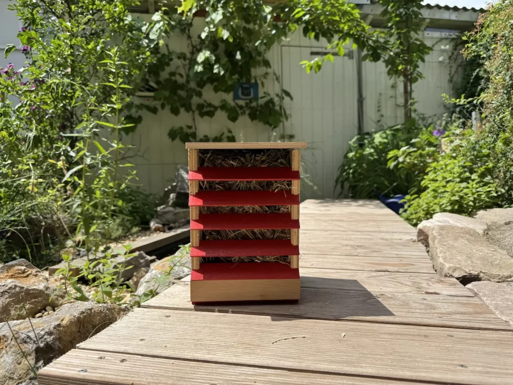 Ein Florfliegenkasten steht auf einem Holzsteg im Garten.
