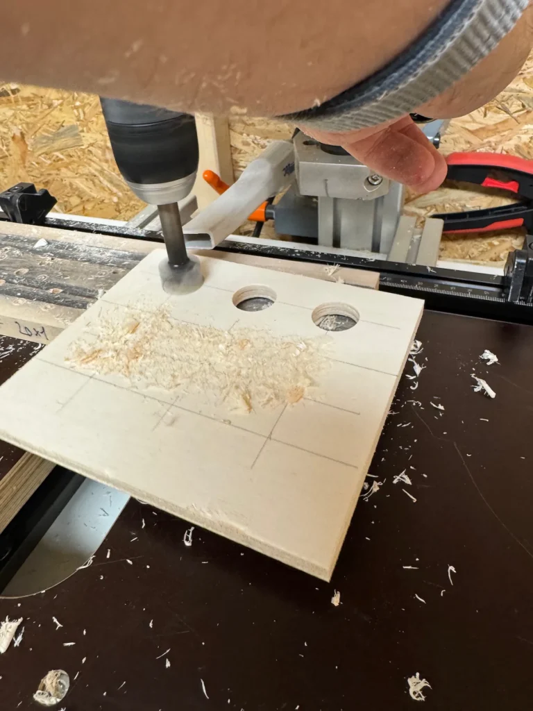 In einer Holzplatte werden mit einem Forstnerbohrer Löcher gebohrt.
