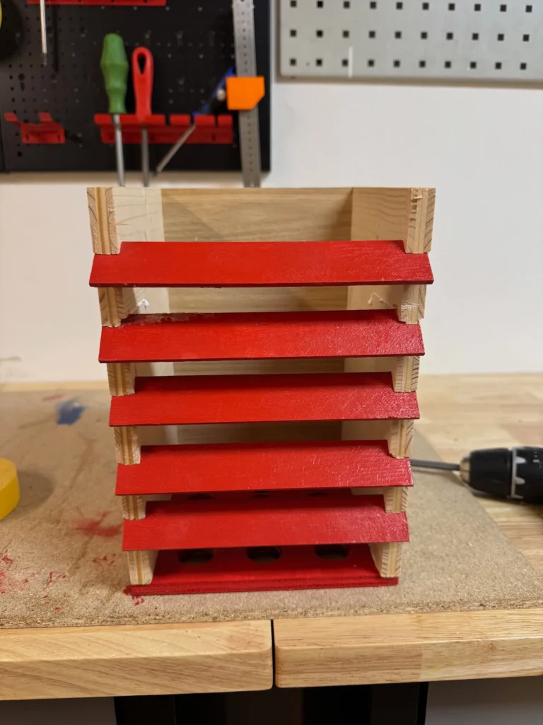 Rote Lamellen stecken in einem Holzkasten.