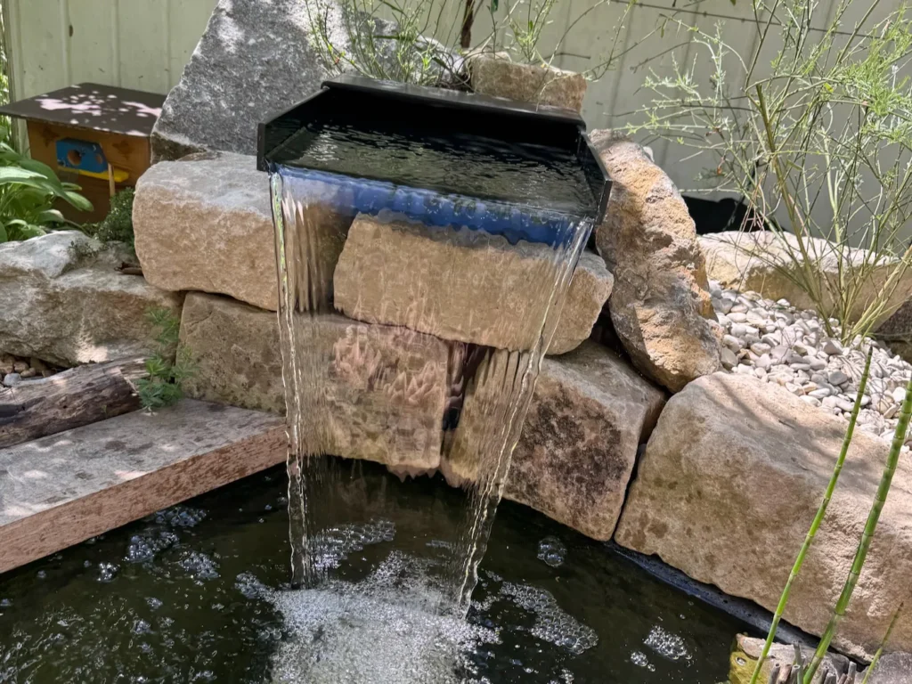 Künstlich angelegter Wasserfall an einem kleinen Teich.