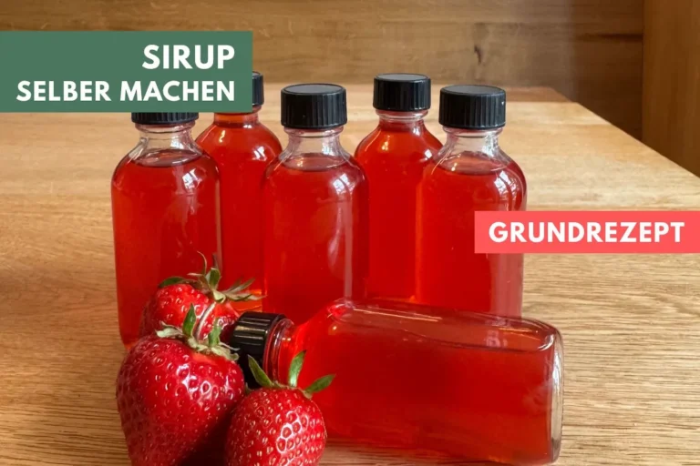Kleine Flaschen mit selbst gemachtem Erdbeer-Sirup stehen auf einem Tisch.