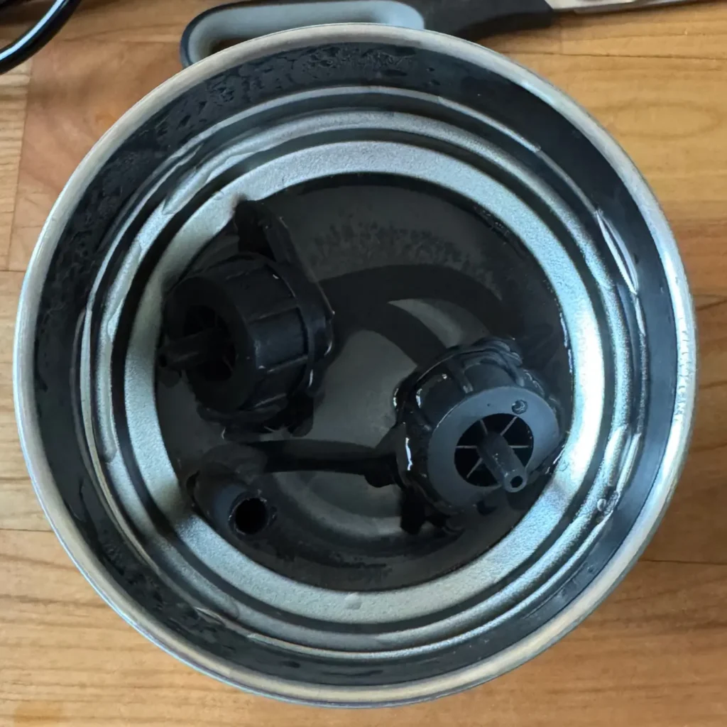 Thermobecher voll mit heißem Wasser und Kunststoffteilen, die darin schwimmen.