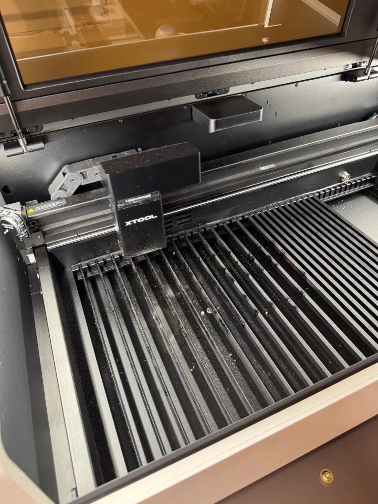 Innenraum des xTool P2 CO₂-Lasers mit verschmutzter Auffangschale und Staubablagerungen.