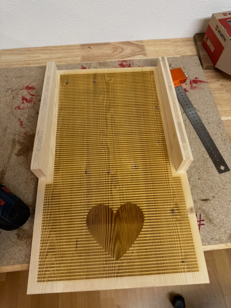 Holzplatte mit Kletterrillen und Herzform, vorbereitet mit dem CO₂-Laser für einen Fledermauskasten.
