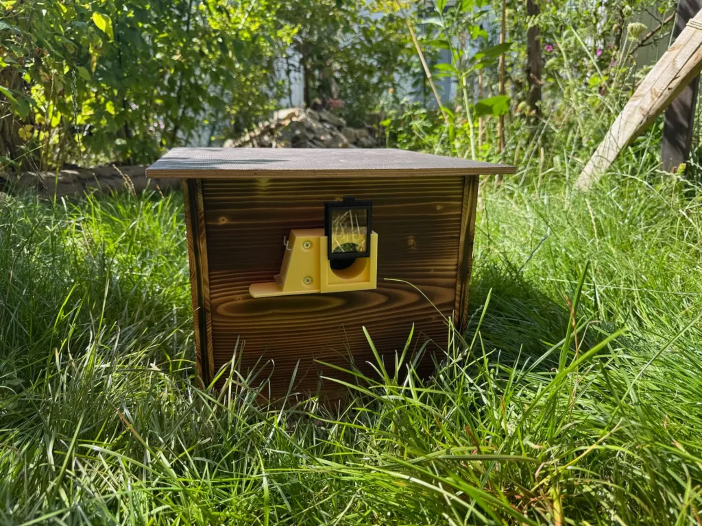 Hummelkasten aus Holz steht in einer grünen Wiese