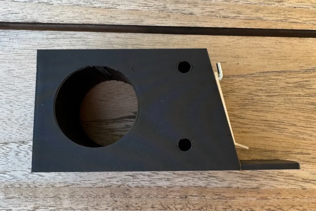 Seitenansicht schwarzer Vorbau mit montierter transparenter Klappe, befestigt mit zwei kleinen L-Haken.