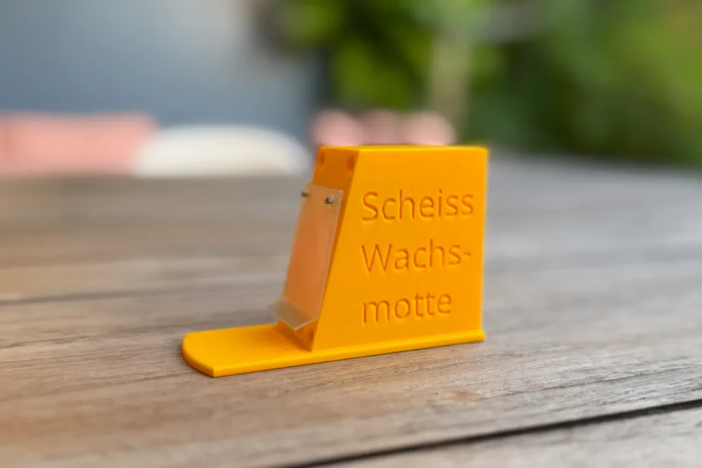 Gelber Vorbau mit transparenter Klappe, seitliche Ansicht, Schriftzug „Scheiss Wachsmotte“ gut sichtbar.