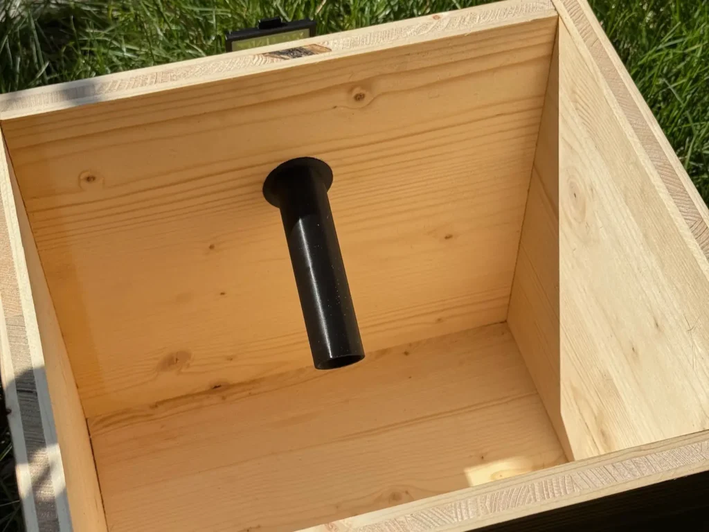 Schwatzes Rohr im Inneren eines hölzernen Hummelkastens