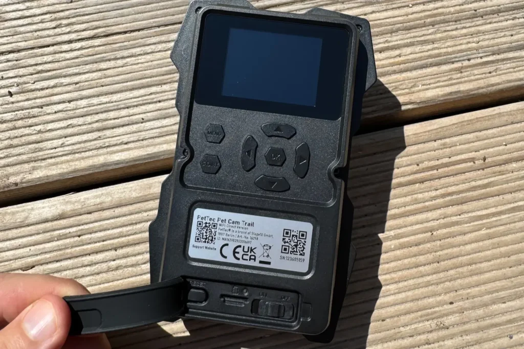 Rückseite der PetTec Pet Cam Trail mit Bedientasten, geöffnetem Fach und Ein-/Aus-Schalter.