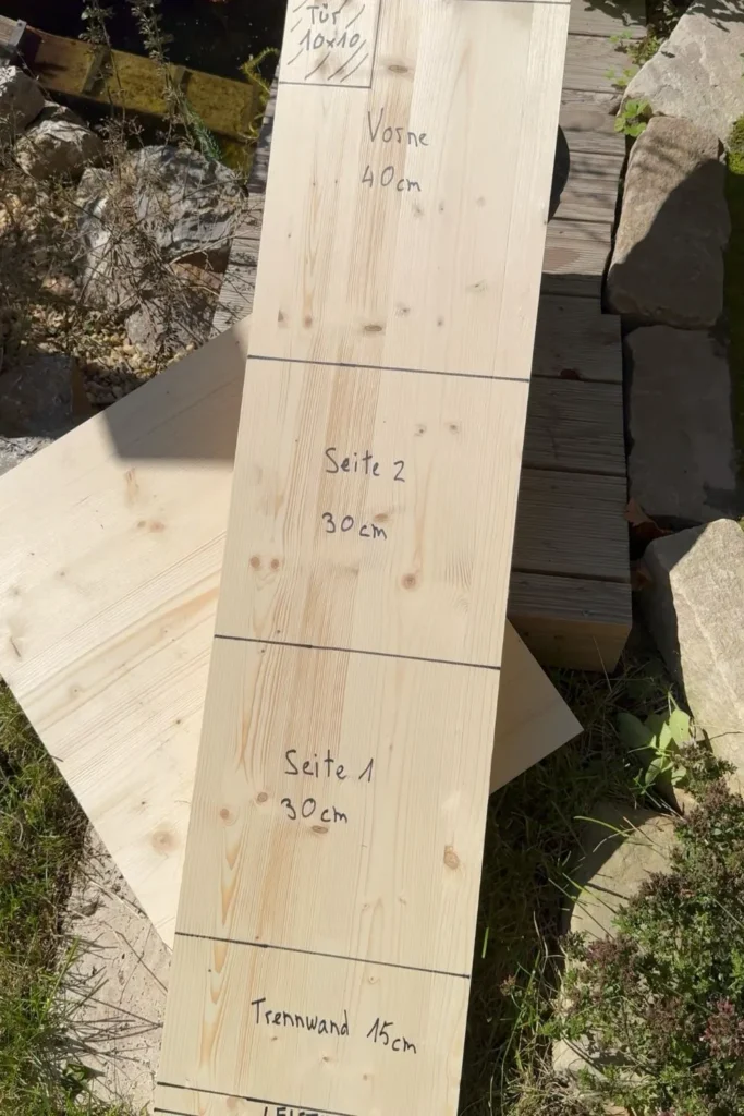 Langes Holzbrett mit angezeichneten Zuschnitten für Vorderseite, Seiten und Trennwand des Igelhauses.