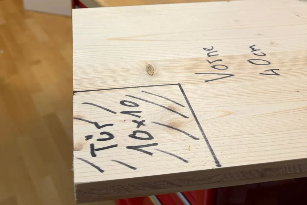 Holzbrett mit aufgezeichnetem 10x10 cm Eingang für das Igelhaus.