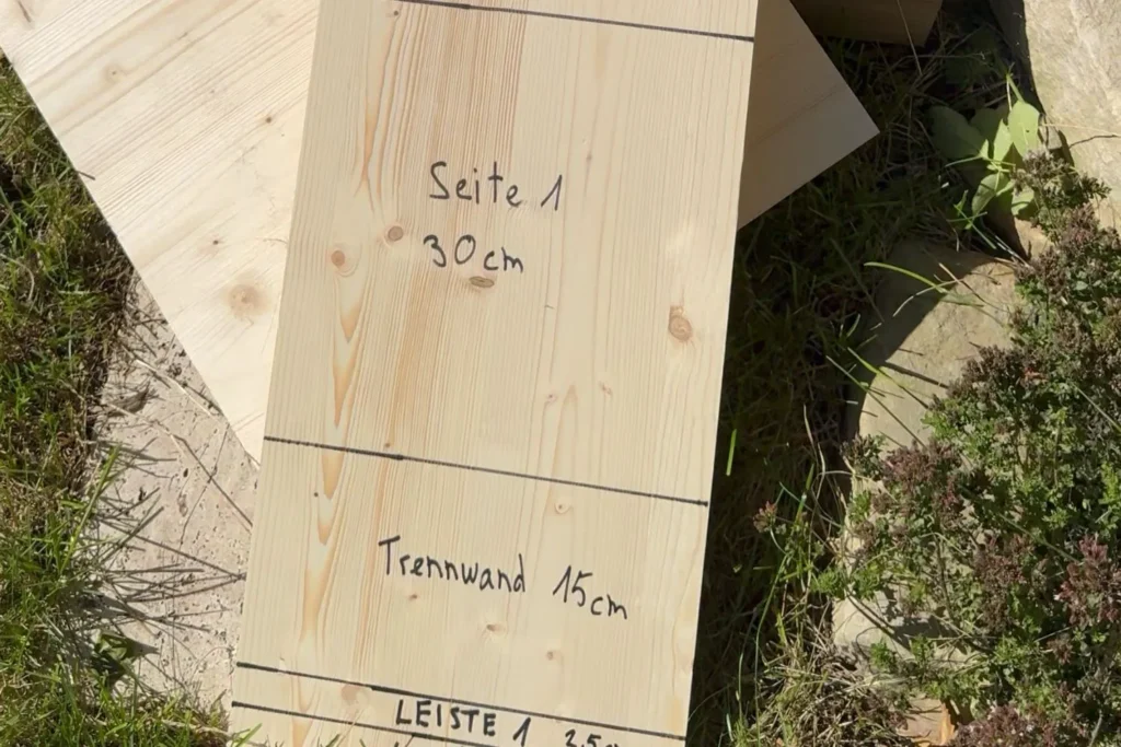 Langes Holzbrett mit angezeichneten Zuschnitten für Vorderseite, Seiten und Trennwand des Igelhauses.