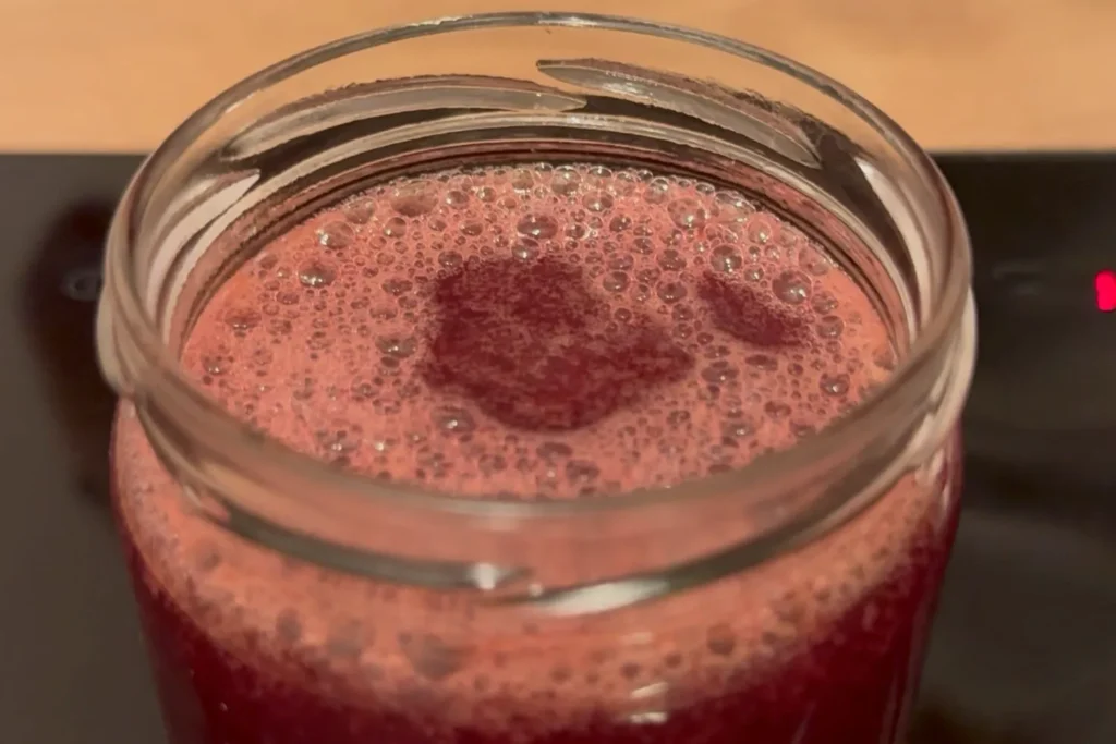 Heiße Weintraubenmarmelade frisch in ein Glas abgefüllt.