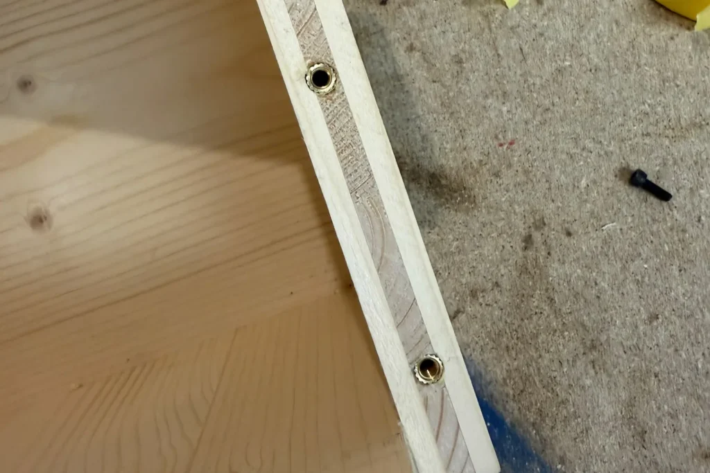 Eingesetzte Gewindeeinsätze in der Seitenwand eines selbstgebauten Eichhörnchen-Futterhauses.