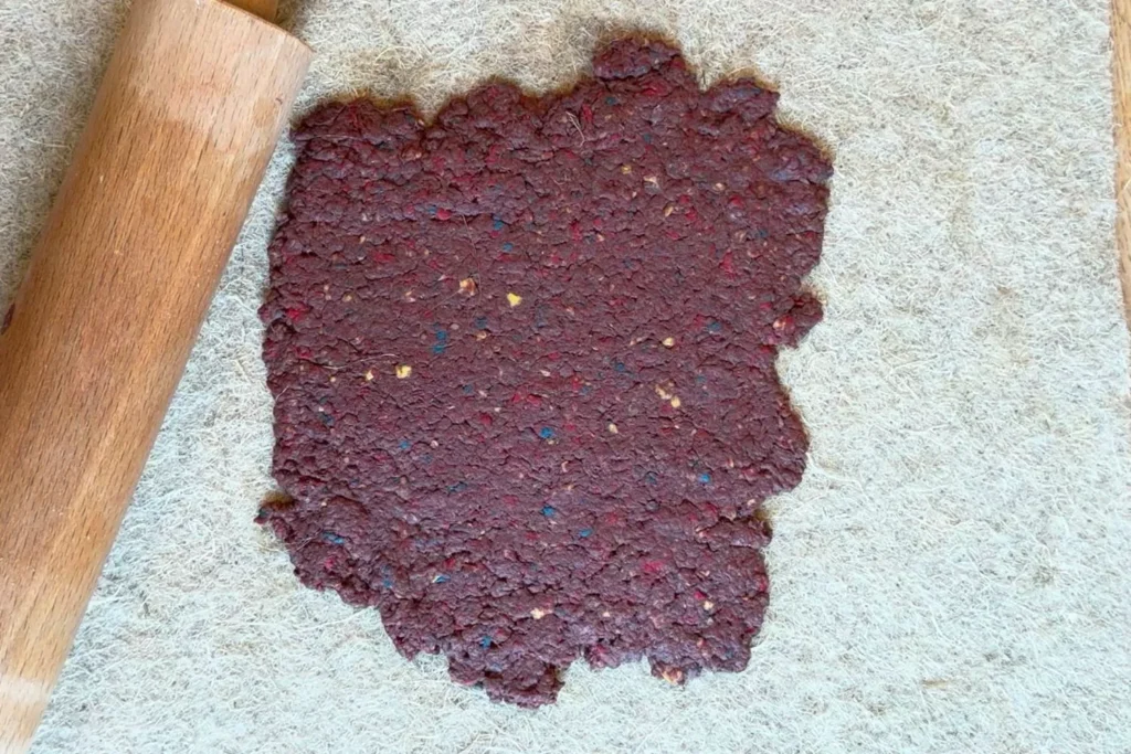 Dunkelrote Papiermasse auf Filztuch ausgerollt â Grundlage fĂŒr Blumenkonfetti.