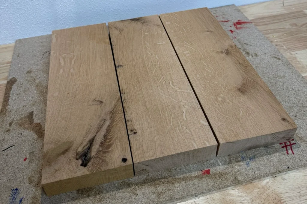 Drei zugeschnittene Eichenbretter liegen bereit für die Bodenplatte des DIY-Kratzstamms.