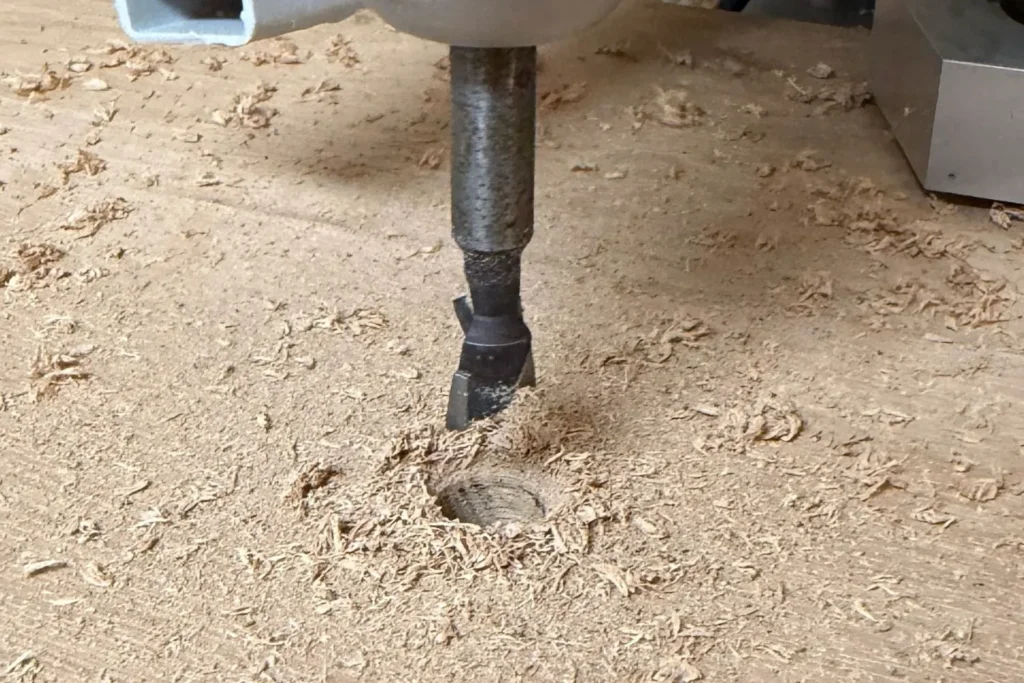 Forstnerbohrer bohrt Loch in die Bodenplatte für die Einschraubmutter des DIY-Kratzstamms.