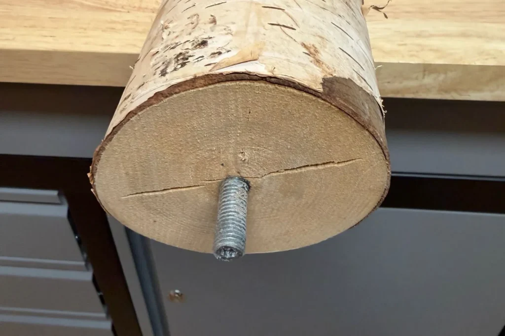 Stockschraube wird in den Birkenstamm eingedreht, um ihn mit der Bodenplatte zu verbinden.
