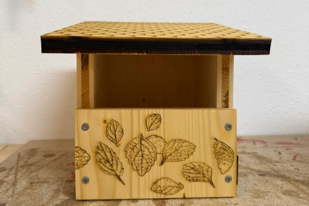 Die Vorderseite des Nistkastens ist mit gelaserten Blättern dekoriert, natürliche Optik.