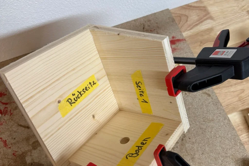 Die Seitenteile des Nistkastens werden ausgerichtet und mit Zwingen verpresst.