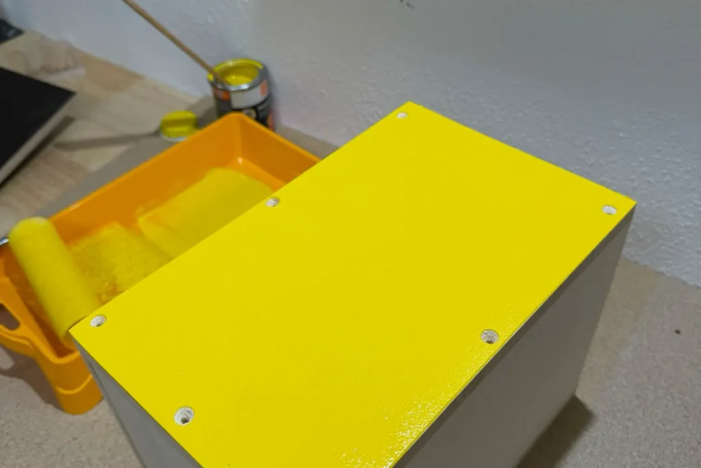 Gelb gestrichene Außenseite eines Schmetterlingshauses während des Anstrichs.