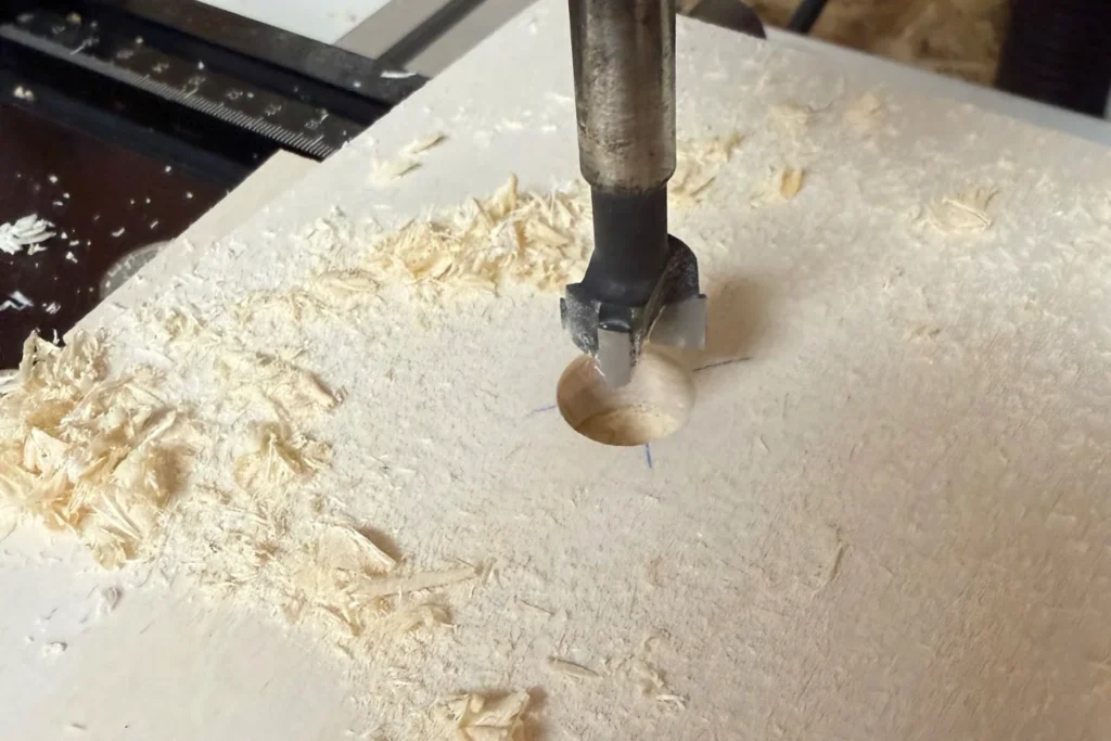 Forstnerbohrer bohrt ein 1-cm-Ablaufloch in die Bodenplatte eines Schmetterlingshauses.