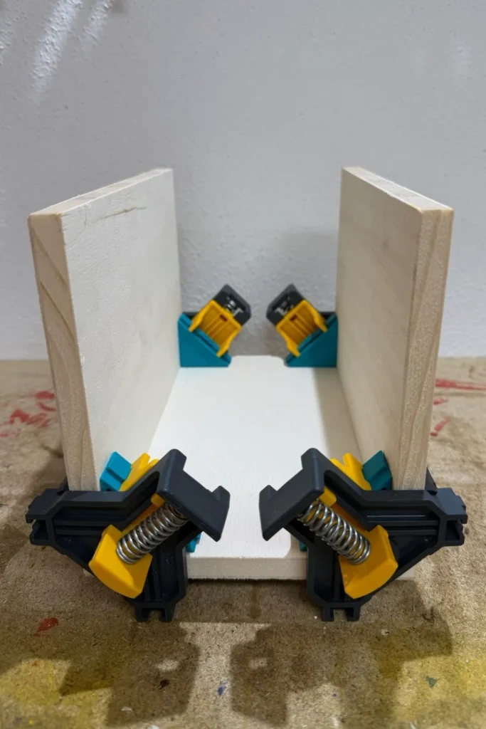 Verleimte Seitenteile eines Schmetterlingshauses, gehalten von Eckzwingen.