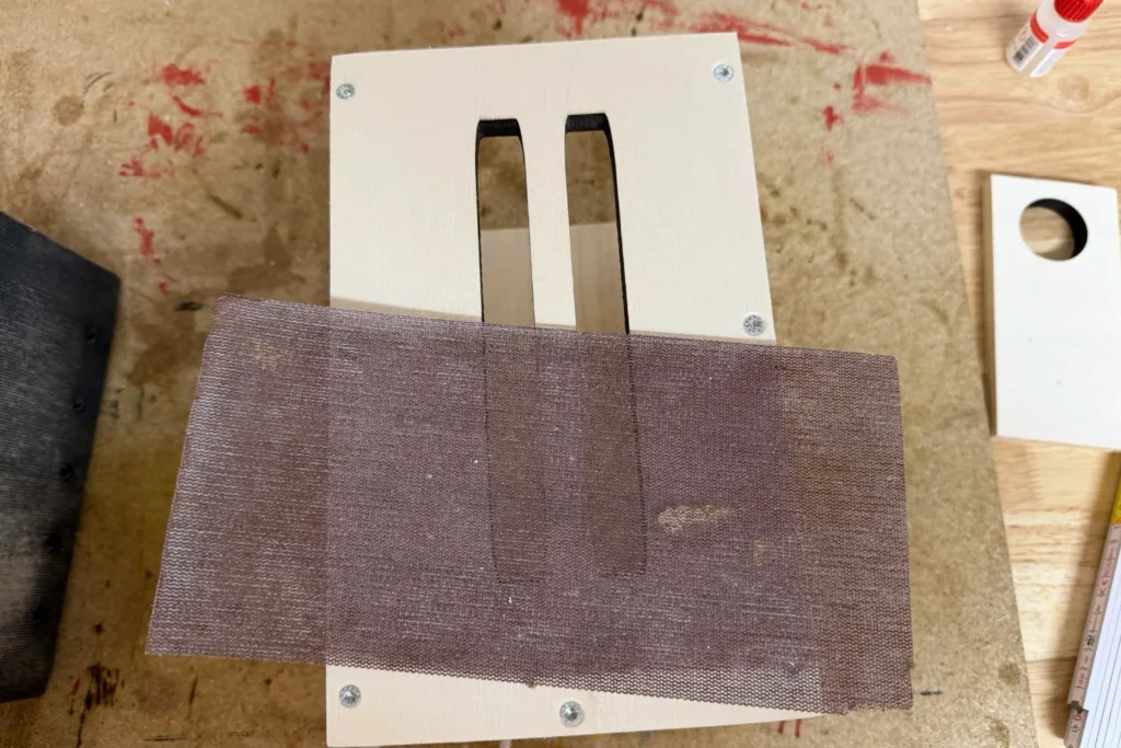 Schmetterlingshaus mit Schleifvlies, das zum Glätten der Einflugschlitze verwendet wird.