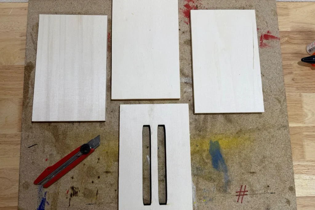 Vier gleich große Holzplatten für den Bau eines Schmetterlingshauses, inklusive Vorderseite mit Schlitzöffnungen.