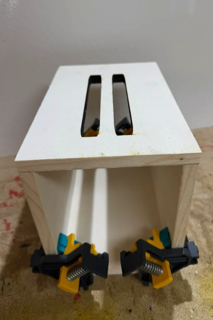 Verleimte Seitenteile eines Schmetterlingshauses, fixiert mit Eckzwingen.