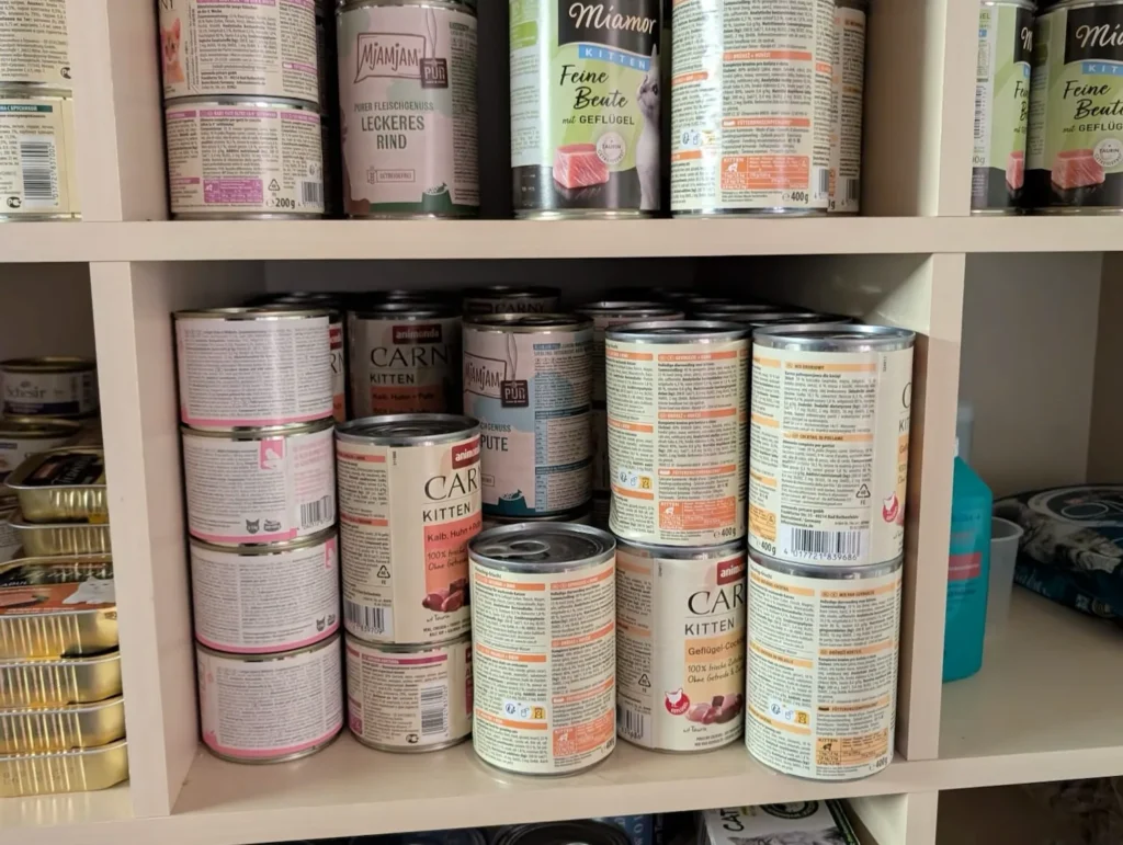 Vorratsschrank mit verschiedenen Katzenfutter-Dosen, ideal zur Fütterung von Jungigeln und Pflegeigeln.