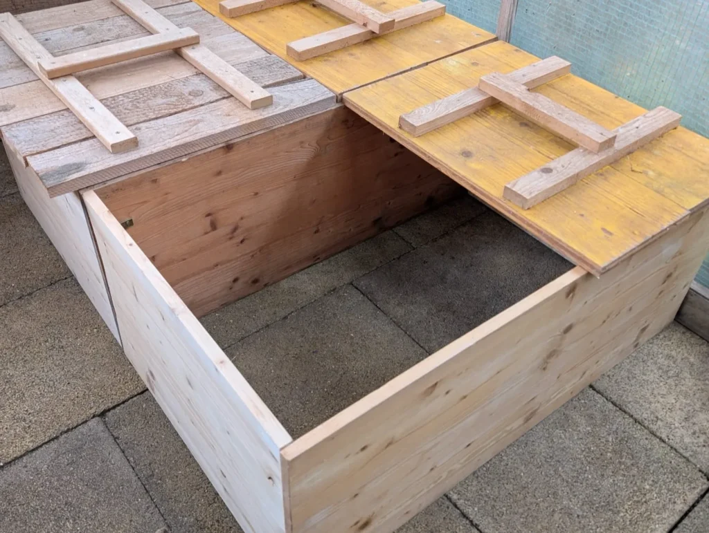 Offenes Holzgehege mit mehreren Abteilen und stabilen Abdeckungen, vorbereitet für die Igelüberwinterung.