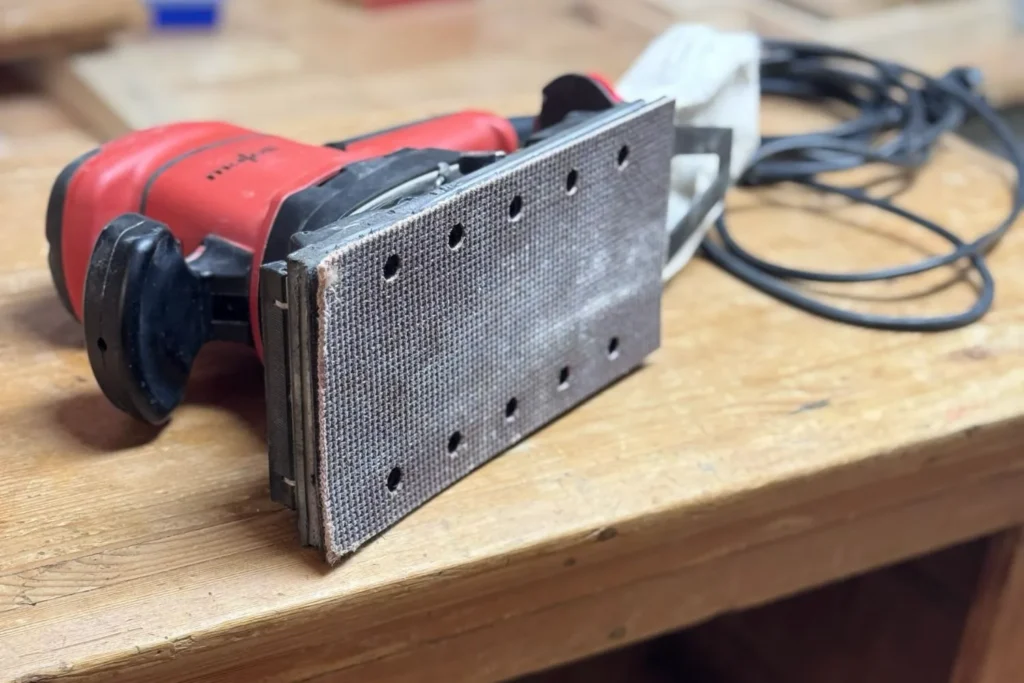 Detailaufnahme eines Schwingschleifers mit benutztem Schleifpapier