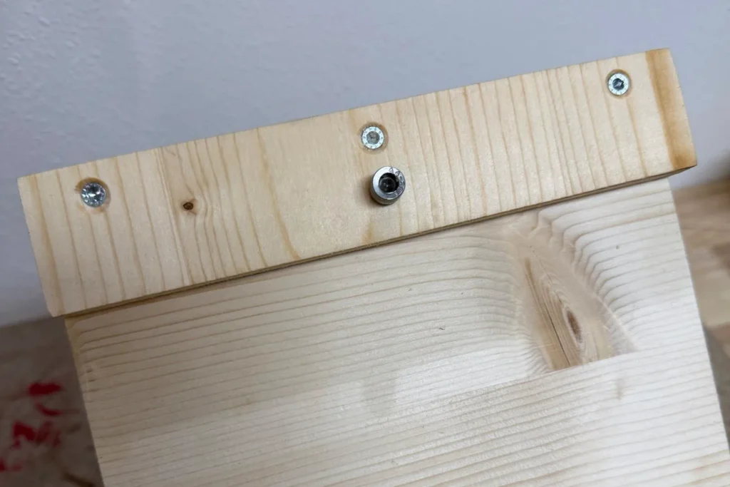 Detailansicht des Dachs eines Vogelfutterhauses mit Schraube als Verschlussmechanismus.