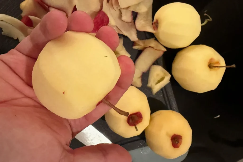 Frisch geschälte Äpfel in der Hand, bereit zum Schneiden für Apfelkompott.