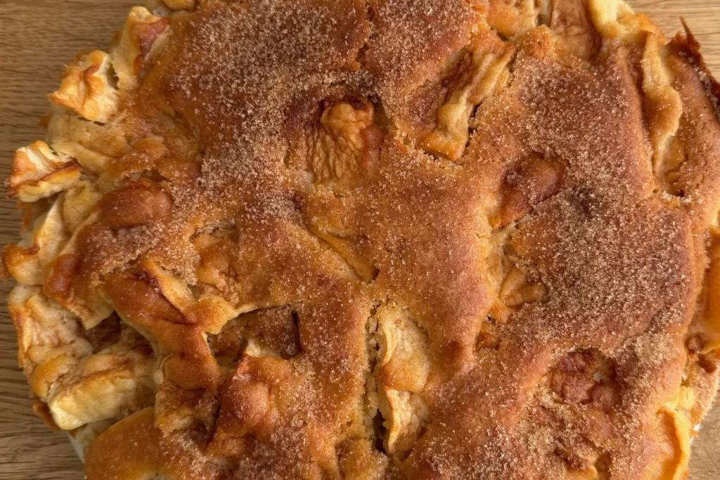 Ganzer Apfelkuchen von der Seite, goldbraun gebacken.