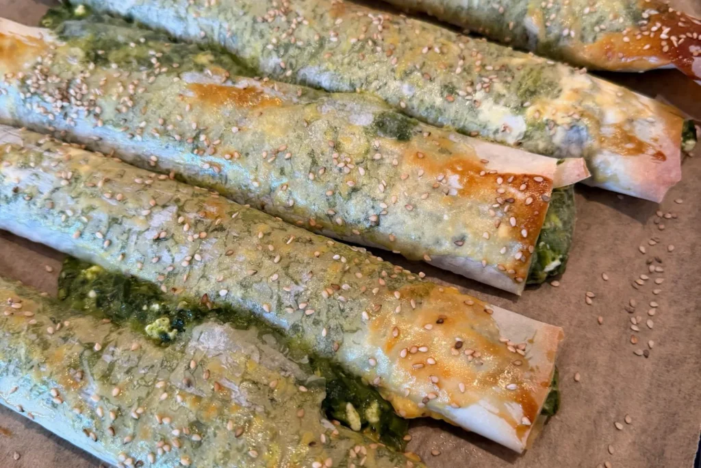 Knusprig gebackene Börek mit Spinat und Feta, mit Eigelb bestrichen und mit Sesam bestreut.