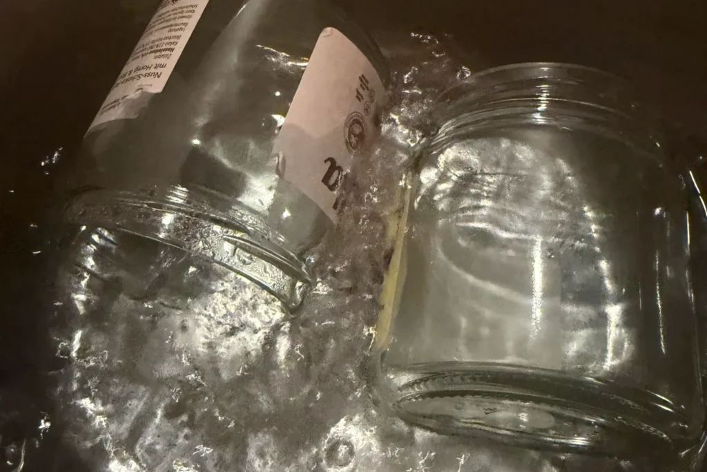 Einmachgläser werden in kochendem Wasser sterilisiert, um Apfelkompott hygienisch abzufüllen.