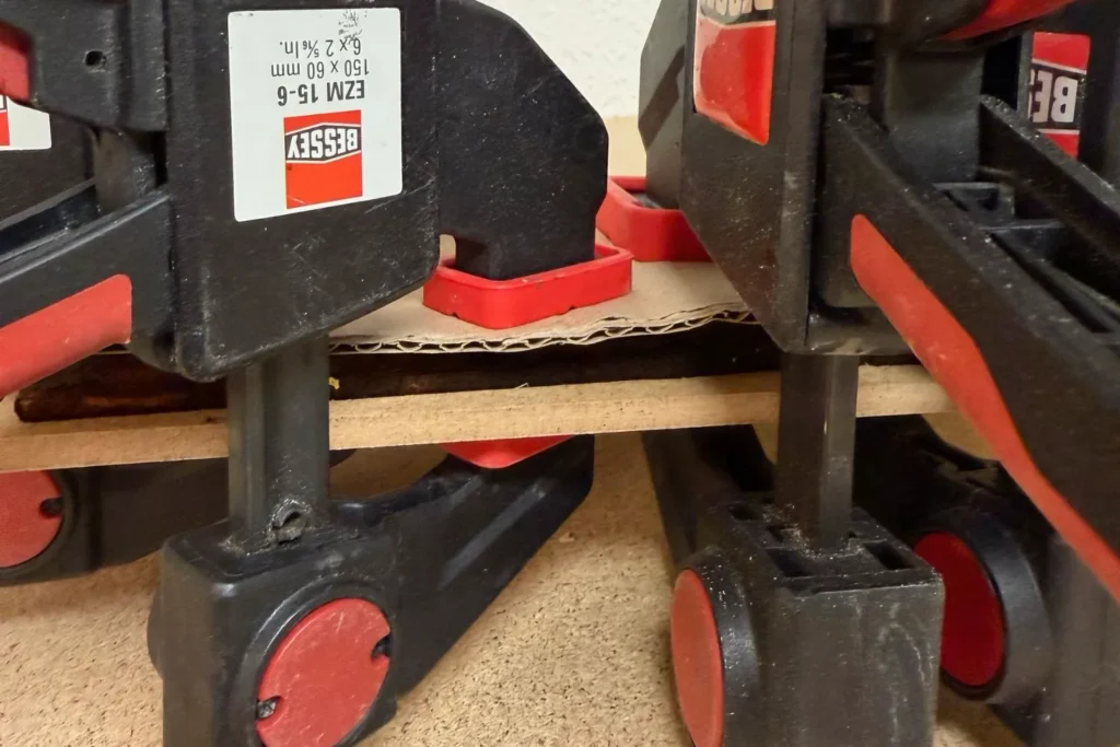 Erwärmte Rinde liegt unter einer Pressplatte, um beim Trocknen flach zu bleiben.