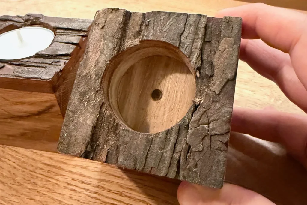 Nahaufnahme eines gebohrten Teelichthalters mit natürlicher Rindenoberfläche.