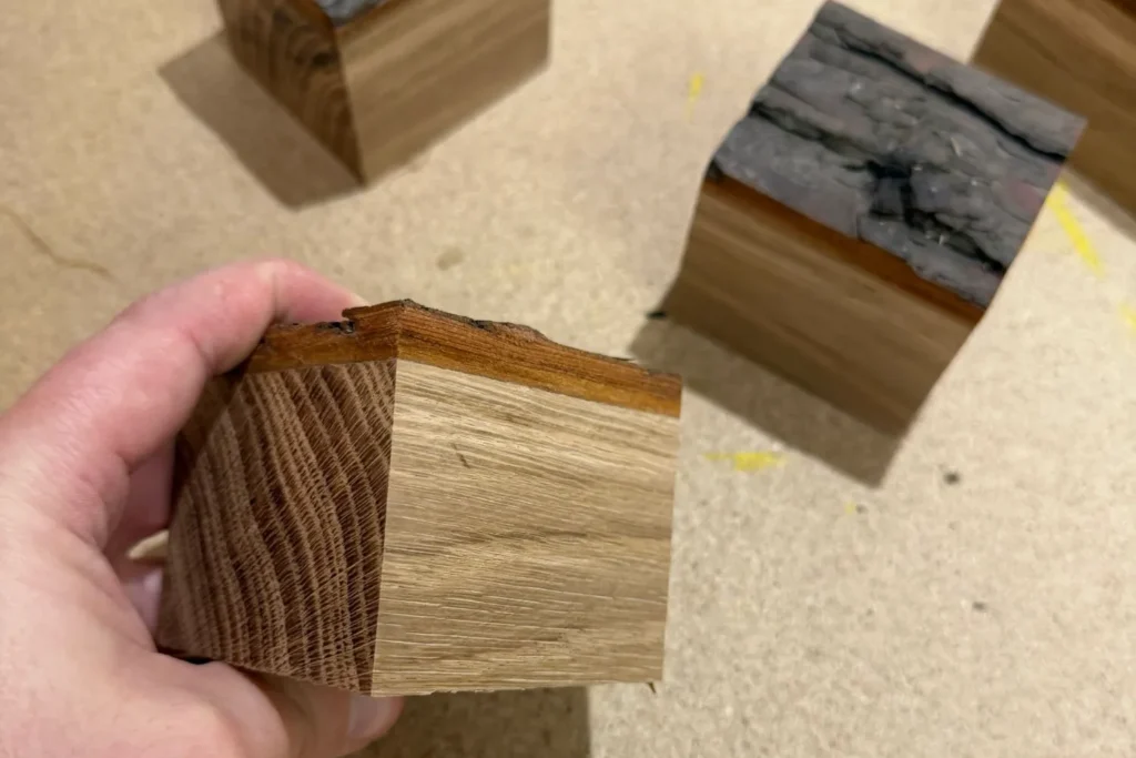 Ein zugeschnittener Würfel aus Eiche mit Rindenoberfläche wird in der Hand gehalten.