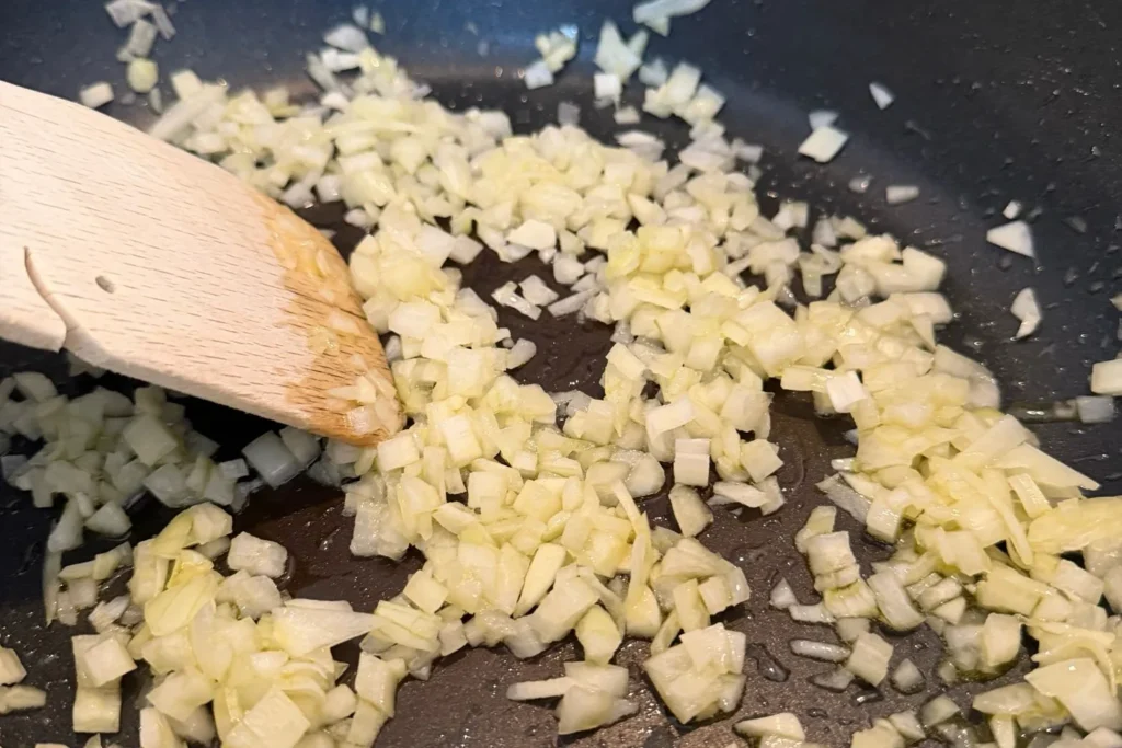Fein gewürfelte Zwiebeln werden glasig angedünstet – Basis für die würzige Börek-Füllung mit Spinat und Feta.