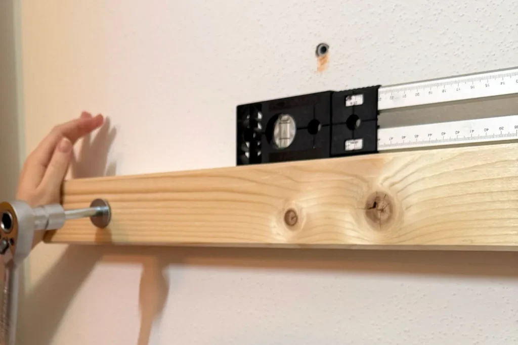 Waagrecht montierter Holzbalken eines Hochbetts mit Wasserwaage ausgerichtet und angeschraubt.