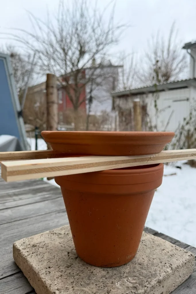 Frostfreie Vogeltränke mit Tontopf und Untersetzer auf Holzleisten